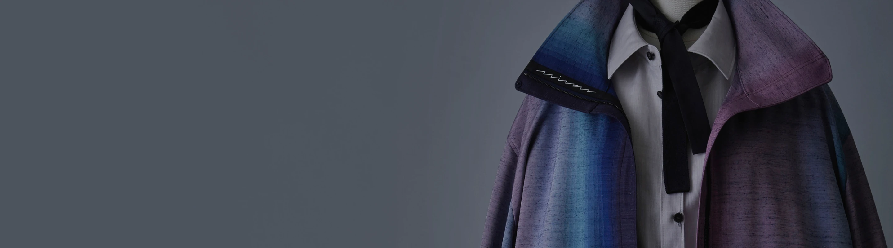 グラデーションのように紫から青へと色が移ろう羽織を着せたトルソーの上半身。白いシャツに黒いリボンタイを合わせ、上品で落ち着いた雰囲気の装いが強調されている。