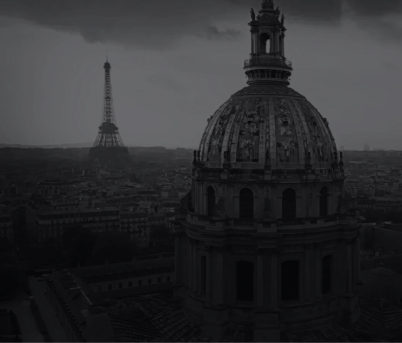 曇り空の下、パリの街並みにそびえるドーム屋根の建物を前景に、左奥にはエッフェル塔がかすんで見えるモノクロ写真。